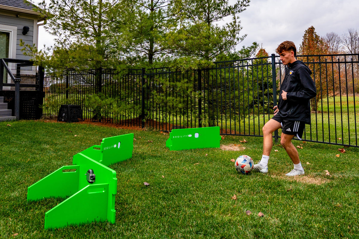 Soccer player controlling a ball among three ReboundIQ boards arranged at different angles on grass