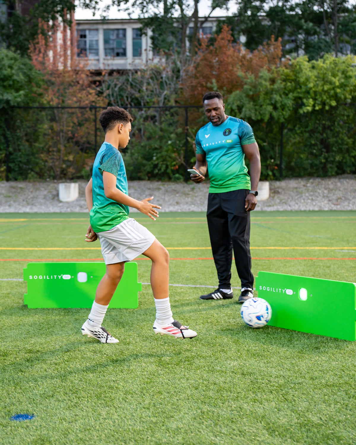 Coach watching a player work between ReboundIQ boards on a soccer field