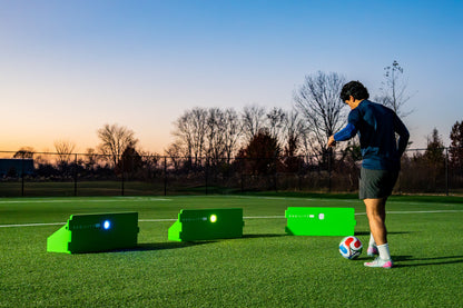 Player training at dusk with three ReboundIQ boards and glowing Impact Lights