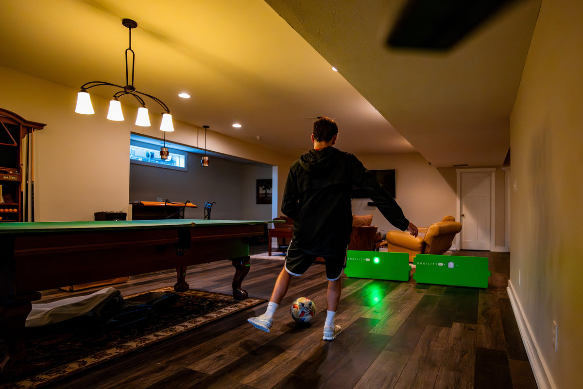 Player training indoors in a finished basement with two ReboundIQ boards and glowing Impact Lights